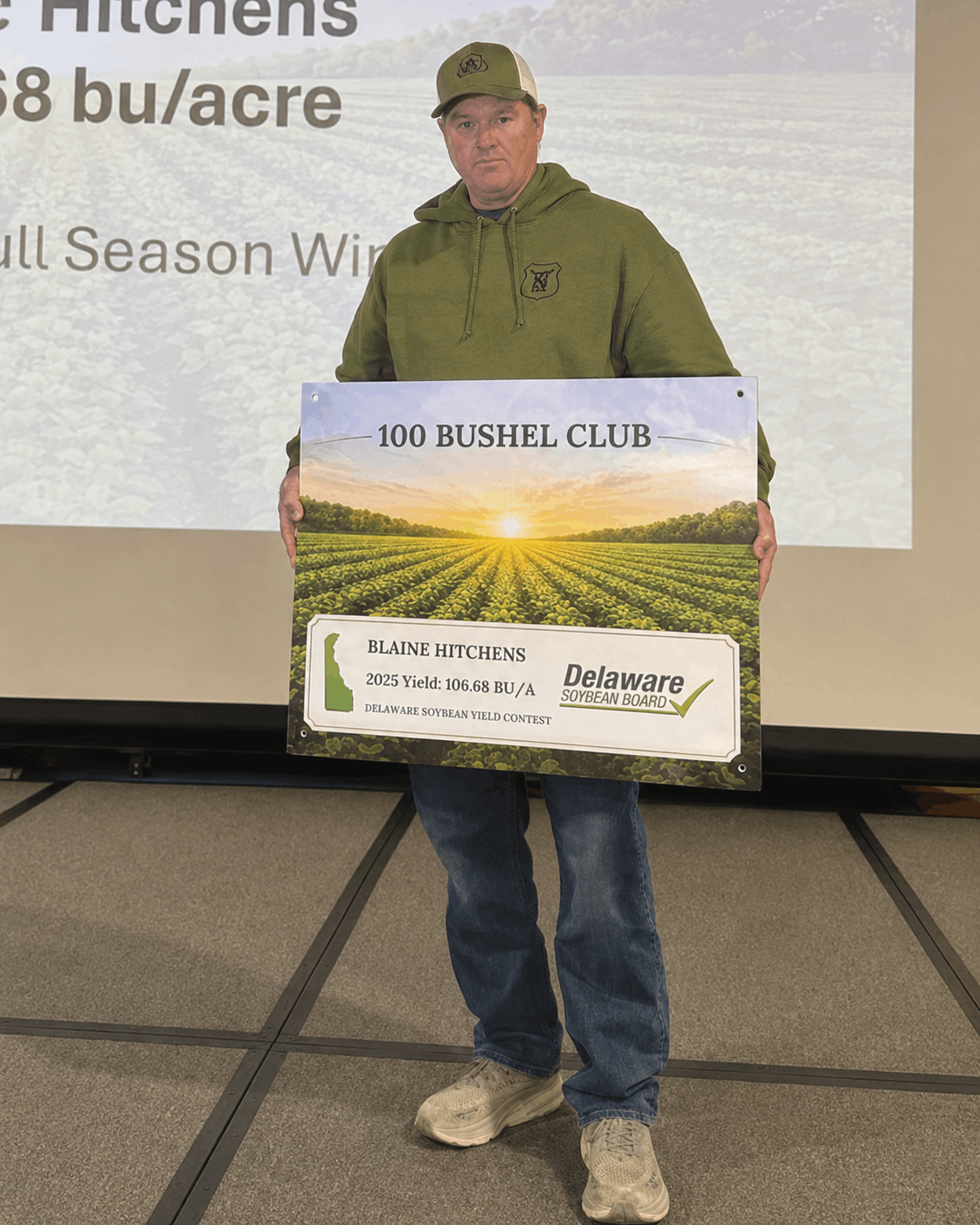 Man holding 100 Bushel Club award sign